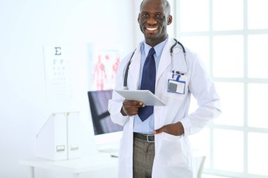 Tablet bilgisayarlı siyahi bir doktor hastanede bekliyor.