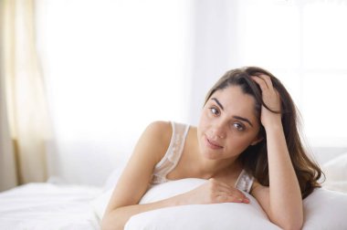 Güzel bir kadın yatağında uzanıyor.