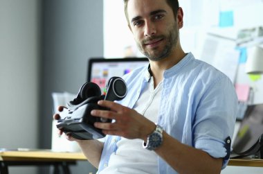 Genç erkek yazılım programcısı ofiste üç boyutlu sanal gerçeklik gözlükleriyle yeni bir uygulama test ediyor..