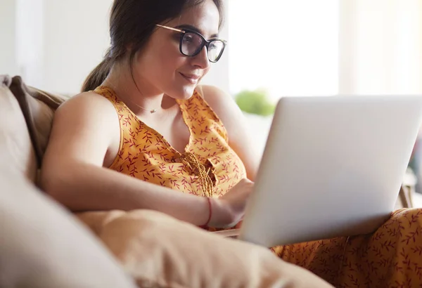 Giovane donna seduta sul divano che lavora sul computer portatile a casa — Foto Stock