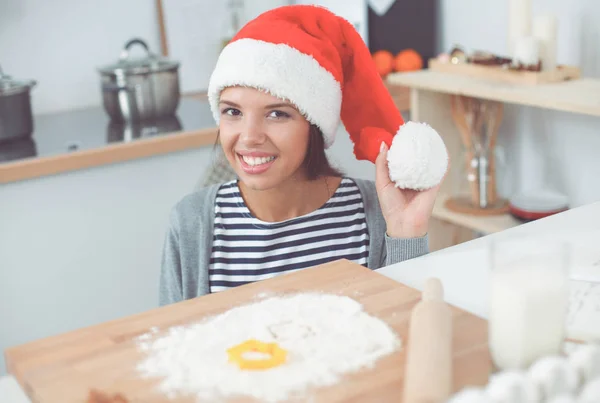 Γυναίκα με καπέλο santa κάνει χριστουγεννιάτικα μπισκότα στην κουζίνα — Φωτογραφία Αρχείου