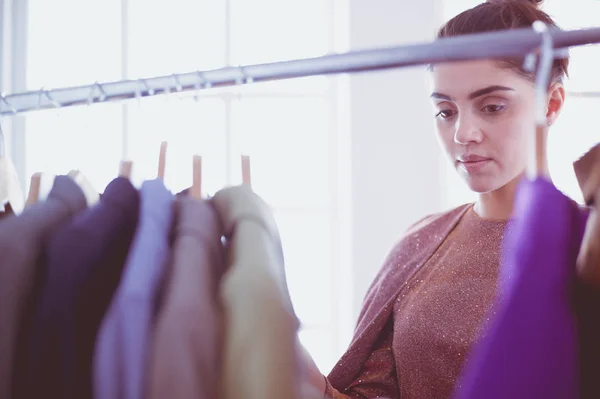 Mooie jonge stylist bij rek met hangers — Stockfoto