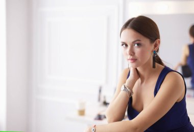 Beyaz arka planda izole edilmiş bir sandalyede oturan genç kadın.