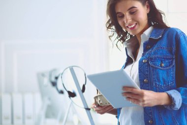Gülümseyen kadın kahve içiyor ve kafede tablet kullanıyor.