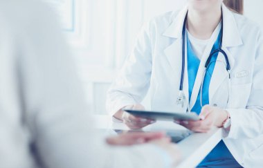 Kadın doktor hastane lobisinde tablet bilgisayar kullanarak, gülümseyerek