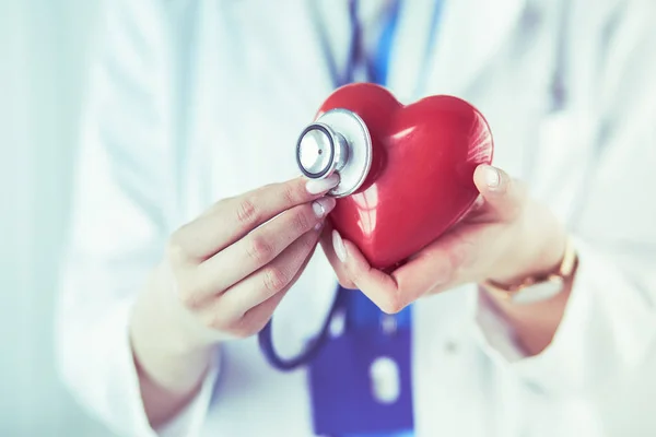 Un medico con stetoscopio che esamina il cuore rosso, isolato su sfondo bianco — Foto Stock