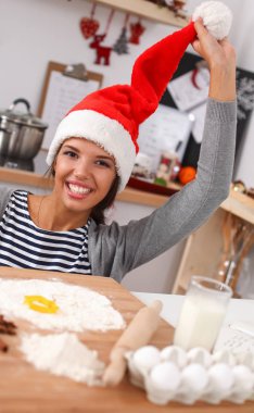 Noel Baba şapkalı kadın mutfakta Noel kurabiyesi yapıyor.