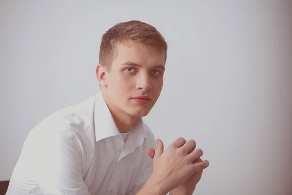 Portrét mladého muže s úsměvem, sedí na šedém pozadí. Portrét mladého muže — Stock fotografie