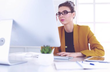 Ofis masasında çalışan ve dizüstü bilgisayarla yazan kendine güvenen genç bir iş kadını.