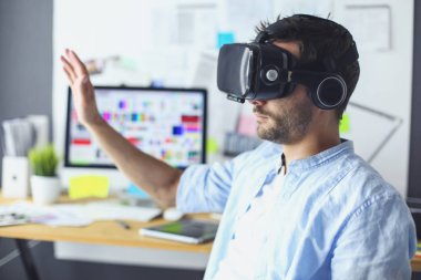 Genç erkek yazılım programcısı ofiste üç boyutlu sanal gerçeklik gözlükleriyle yeni bir uygulama test ediyor..