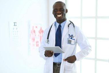 Tablet bilgisayarlı siyahi bir doktor hastanede bekliyor.