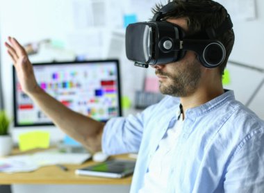 Genç erkek yazılım programcısı ofiste üç boyutlu sanal gerçeklik gözlükleriyle yeni bir uygulama test ediyor..