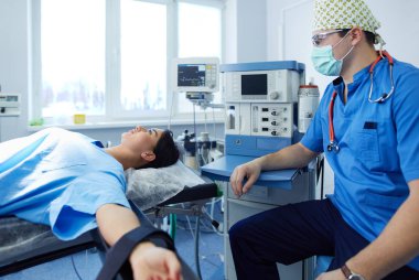 Ameliyat odasında arka planda erkek cerrah var.