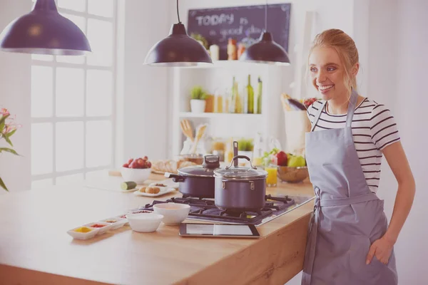 Mujer joven usando una tableta para cocinar en su cocina — Foto de Stock