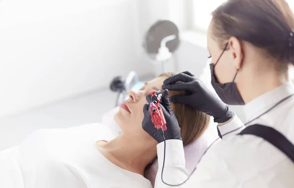 Young woman undergoing procedure of eyebrow permanent makeup in beauty salon — Stock Photo, Image