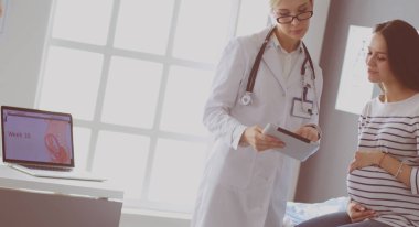 Hastanede doktorla gülümseyen güzel bir hamile kadın.