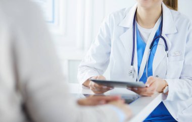 Kadın doktor hastane lobisinde tablet bilgisayar kullanarak, gülümseyerek