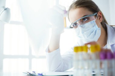 Hastanedeki kan örneğini analiz eden güzel bir kadın laboratuvar asistanı portresi.