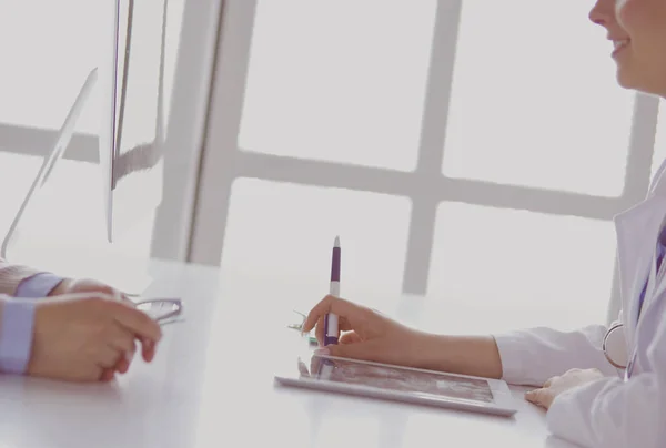 Portrait of middle aged female doctor using digital tablet while sitting at exam room and working — Stock Photo, Image