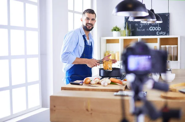 Man holding paper bag full of groceries on the kitchen background. Shopping and healthy food concept — Stock Photo, Image