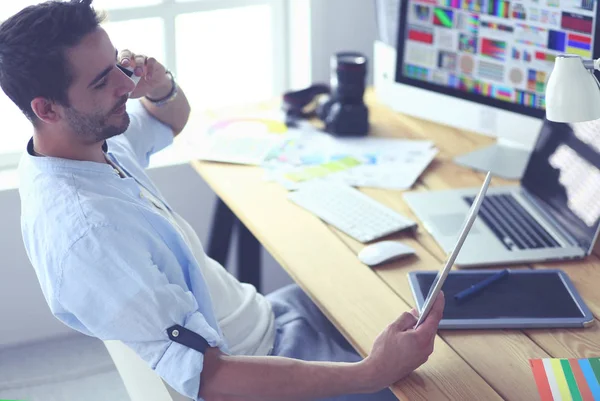 Porträt eines jungen Designers, der im Grafikstudio vor Laptop und Computer sitzt, während er online arbeitet. — Stockfoto