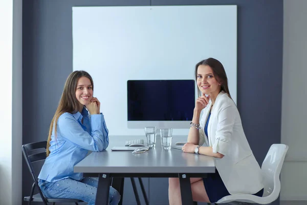 Zwei Bürokolleginnen sitzen auf dem Schreibtisch — Stockfoto