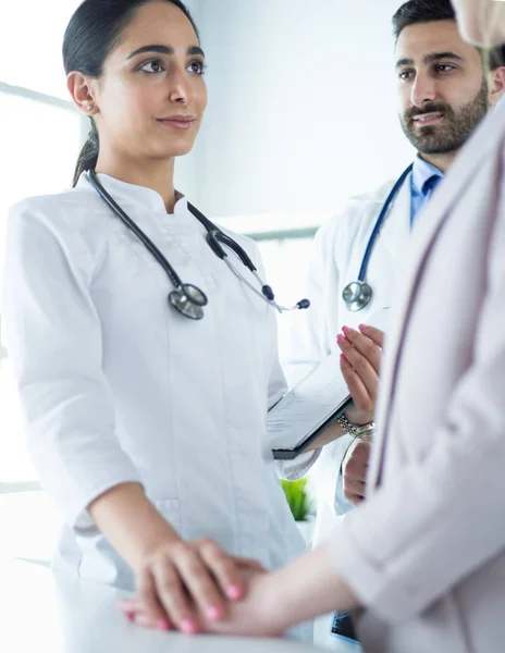 Médico bonito está conversando com jovem paciente do sexo feminino e fazendo anotações enquanto está sentado em seu escritório — Fotografia de Stock