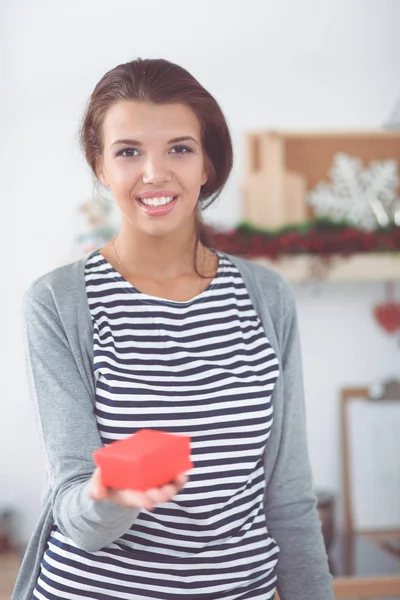 Belle fille tenant une boîte cadeau dans ses mains sur le fond du paysage pour Noël dans la cuisine — Photo