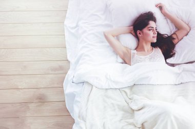 Güzel bir kadın yatağında uzanıyor.