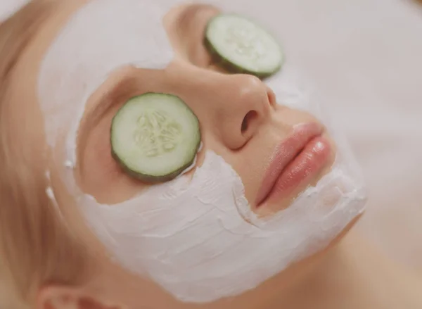 Belle jeune femme recevant un masque facial de concombre dans un salon de beauté — Photo