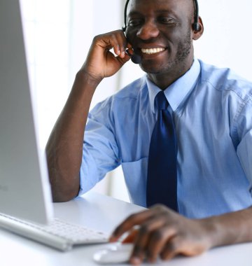 Kulaklıklı Afro-Amerikan işadamı laptopuyla çalışıyor.