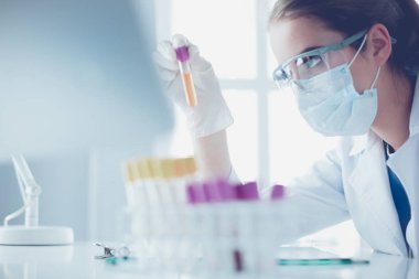 Kadın araştırmacı, beyaz şişeler ve şişelerle çevrili.