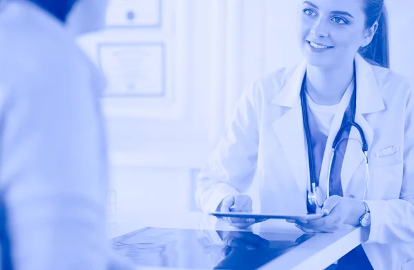 Female doctor using tablet computer in hospital lobby, smiling