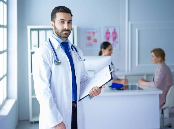 Mosolygó orvos férfi áll a csapata és a beteg előtt. — Stock Fotó
