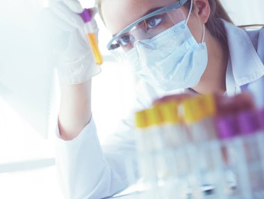 Modern laboratuvar veya hastanede plastik tıbbi tüplerle çalışan araştırmacı, doktor, bilim adamı veya laboratuvar asistanı.