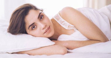Güzel bir kadın yatağında uzanıyor.