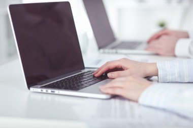 İş kadını ofis masasında oturuyor ve dizüstü bilgisayar elleriyle yazıyor