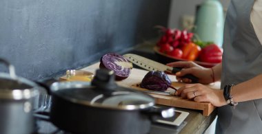 Masanın yanında duran mutfakta sebze doğrayan genç bir kadın.