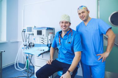 Ameliyat odasında arka planda erkek cerrah var.