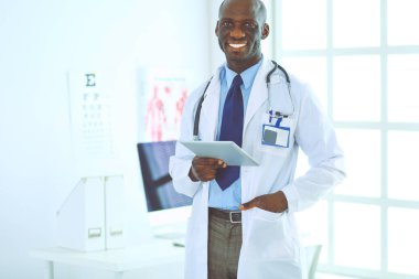 Tablet bilgisayarlı siyahi bir doktor hastanede bekliyor.