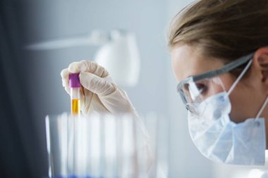 Laboratuvarda sıvı yeşil çözeltiye bakan bir tıbbi veya bilimsel araştırmacı ya da doktor