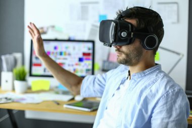 Genç erkek yazılım programcısı ofiste üç boyutlu sanal gerçeklik gözlükleriyle yeni bir uygulama test ediyor..