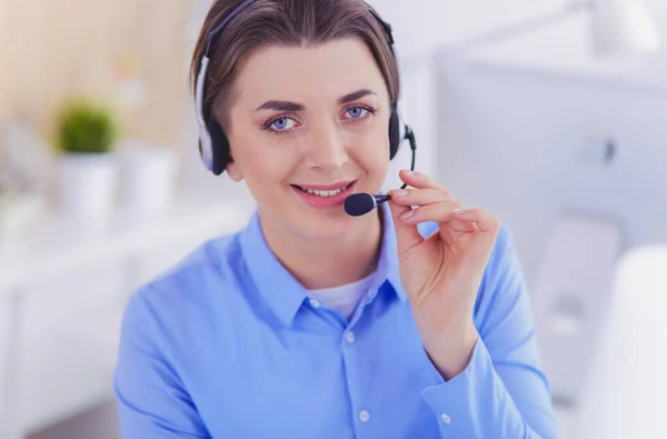 Ernstige mooie jonge vrouw die werkt als support telefoon operator met headset in het kantoor — Stockfoto