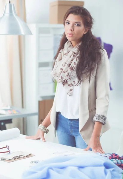 Junge attraktive Modedesignerin steht im Büro am Schreibtisch und hält Ordner in der Hand — Stockfoto