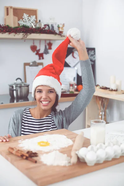 Kvinna i tomte hatt gör julkakor i köket — Stockfoto