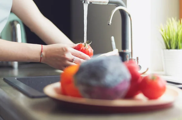 Frau wäscht Tomaten in Küchenspüle aus nächster Nähe — Stockfoto