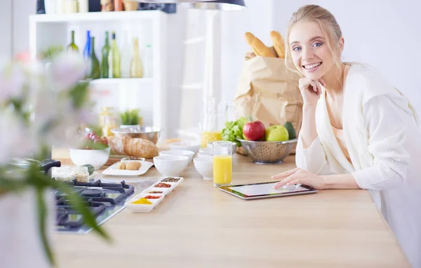 Bella giovane donna utilizzando un tablet digitale in cucina — Foto Stock