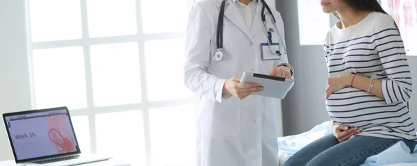 Hastanede doktorla gülümseyen güzel bir hamile kadın.