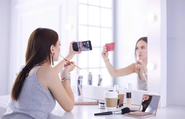 Blogger de belleza filmando tutorial de maquillaje con teléfono inteligente frente al espejo —  Fotos de Stock