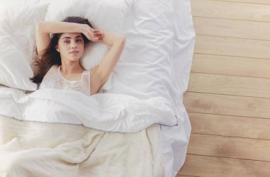 Güzel bir kadın yatağında uzanıyor.